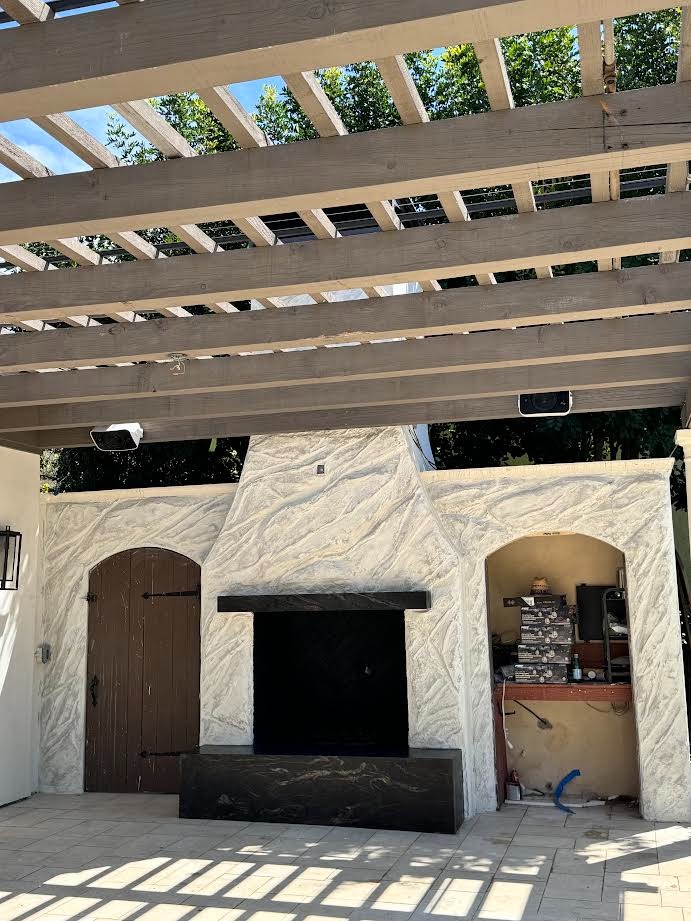 White sculpted stone fireplace under pergola